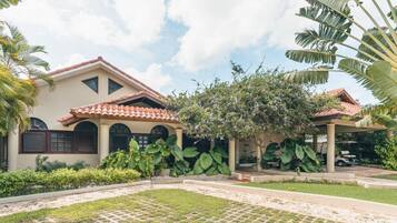 Traditional architecture meets serene surroundings in this charming two-story building, set amidst lush greenery and a well-manicured lawn.