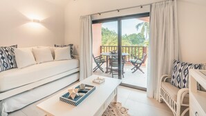 A modern living room with a sofa, a coffee table, and a balcony with outdoor furniture. - 5BR 14 Guests Maid Included Casa de Campo (La Romana)