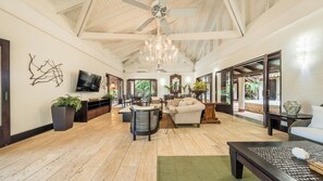 Relax in this stylish living area with a high ceiling, comfortable sofa, and large chandelier.