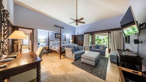 Relax in a classic hotel room with a four-poster bed, sofa, and dining area.