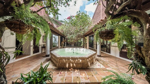 Relax in a serene oasis surrounded by lush greenery and a central hot tub.
