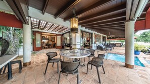 Relax by the pool in this serene outdoor space, featuring a round dining table and wicker chairs.