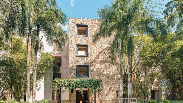 Un edificio con fachada de piedra, varias ventanas y un área de entrada cubierta con escalones.