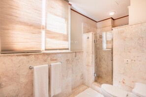 A bathroom with a glass-enclosed shower, a toilet, and a bathtub. - 2br-apartment w Golf View at Casa de Campo (La Romana)