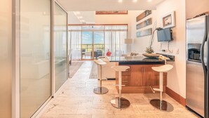 Una cocina moderna con una isla grande, taburetes de bar y un refrigerador.