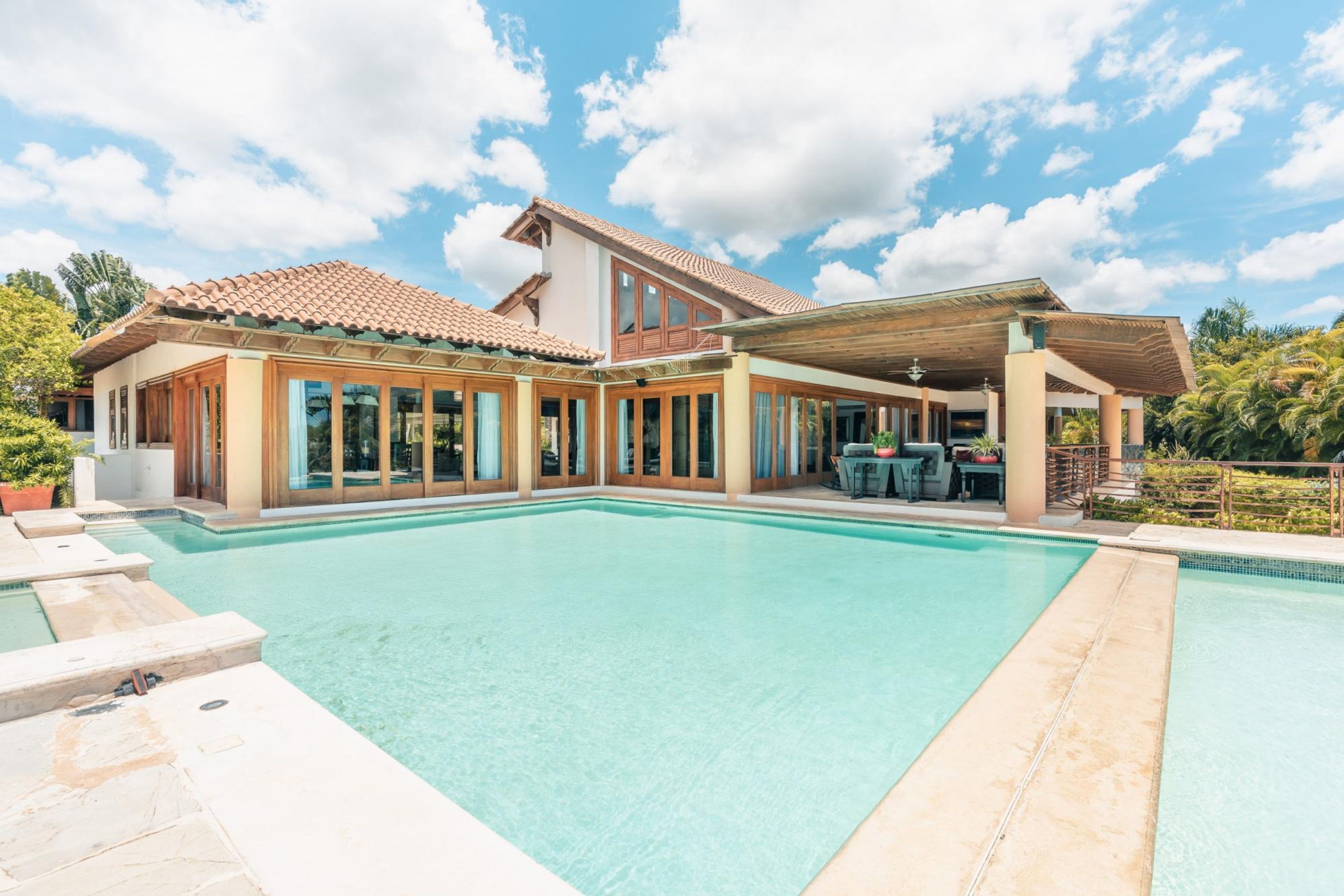 Ein großes Haus mit Pool, überdachter Terrasse und Blick ins grüne Umland.