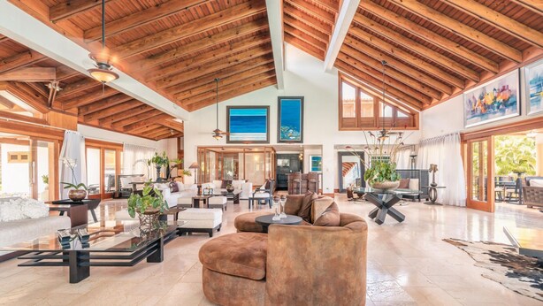 A spacious living area with a high wooden ceiling, comfortable seating, and large windows allowing natural light. - Wonderful Villa w Style at Colinas Casa de Campo (La Romana)