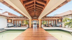 A wooden deck leading to a pool area with outdoor seating and potted plants. - Wonderful Villa w Style at Colinas Casa de Campo (La Romana)