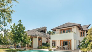 Een tweelaags huis met rieten dak en modern design, voorzien van een zwembad en een terras.