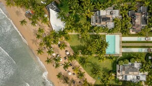 Vue aérienne d’un complexe hôtelier comprenant une plage, une piscine et plusieurs bâtiments.