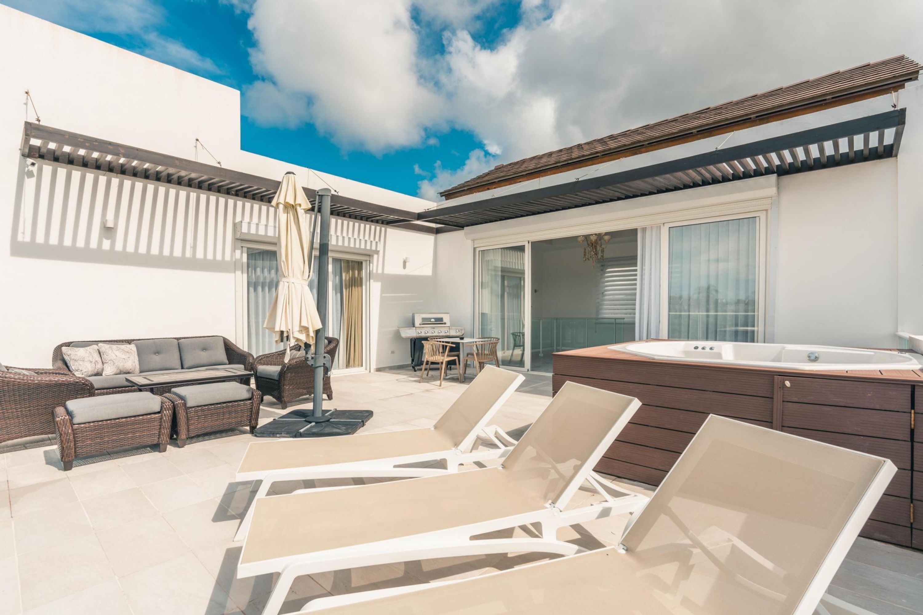 Un espace de vie extérieur moderne comprenant des fauteuils de détente, un jacuzzi et un coin repas.
