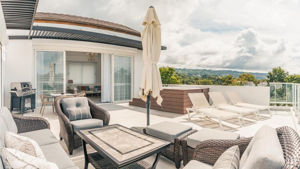 A rooftop patio with wicker furniture, a grill, and a view of the mountains. - 3br-penthouse w Jacuzzi Incl at Lake View (Las Terrenas)