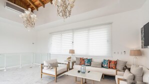 A spacious living room with a white sofa set, a coffee table, and a chandelier. - 3br-penthouse w Jacuzzi Incl at Lake View (Las Terrenas)