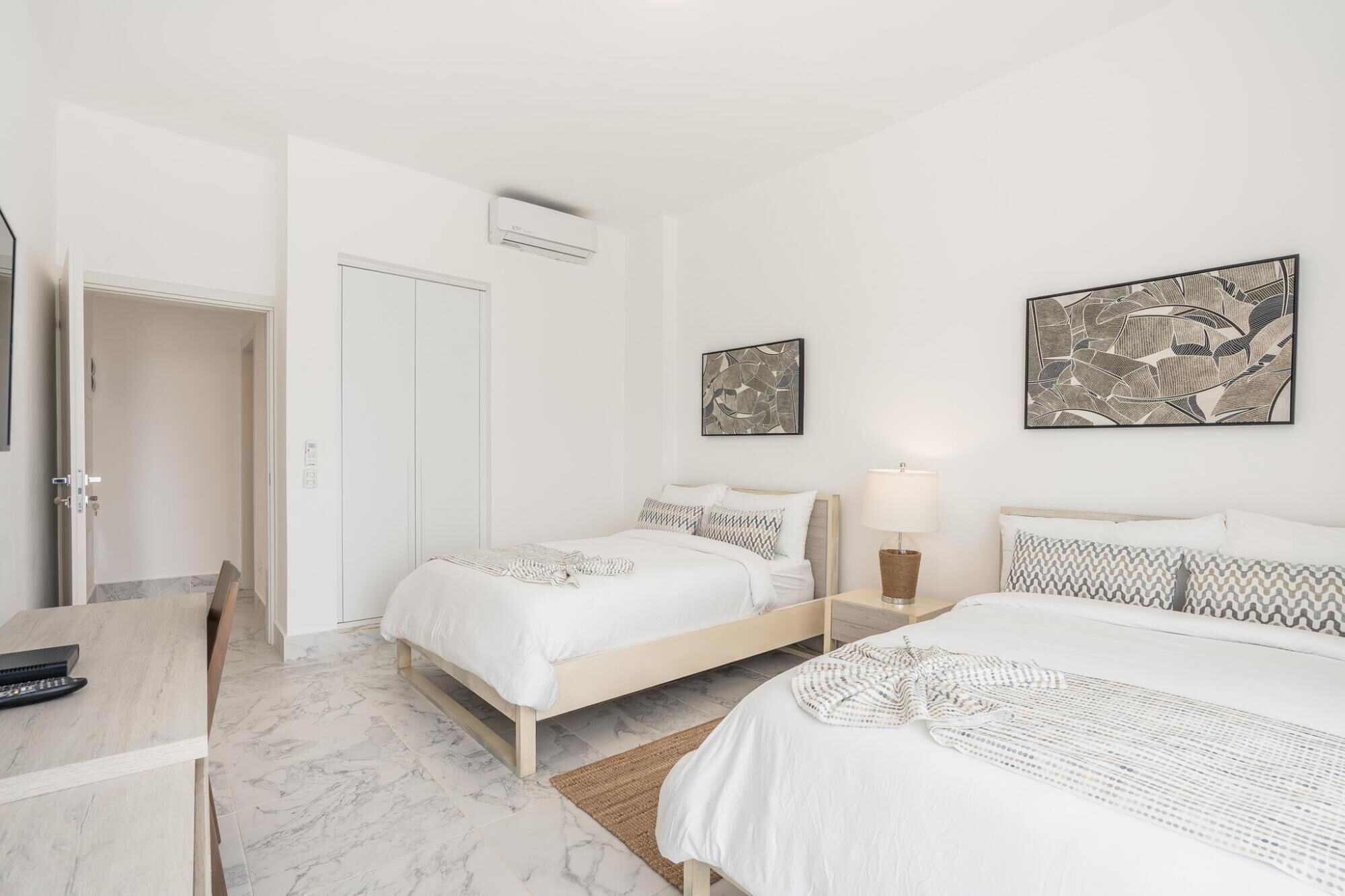 Una habitación de hotel con dos camas, un escritorio y una puerta.