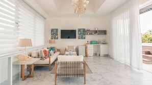 A modern living room with a sofa, a coffee table, and a dining area. There is a kitchen with a microwave and a sink. - 3br-penthouse w Jacuzzi Incl at Lake View (Las Terrenas)