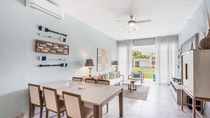 A spacious dining area with a wooden table and chairs, a ceiling fan, and a view of the outdoors. - Two-bedroom apt With Pool View bbq in Lake View (Las Terrenas)