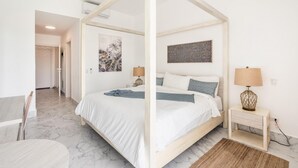 A bedroom with a four-poster bed, a bedside table with a lamp, and a painting on the wall. - Two-bedroom apt With Pool View bbq in Lake View (Las Terrenas)
