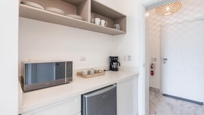 A compact kitchen with a microwave, coffee maker, and storage shelves. - Two-bedroom apt With Pool View bbq in Lake View (Las Terrenas)