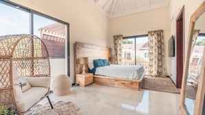 A bedroom with a large bed, a hanging chair, a small table, and a potted plant. - Apartment w 2BR Close to the Beach at Portillo X (Las Terrenas)