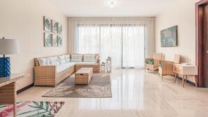 A spacious living room with a sofa, coffee table, and wicker chairs. - Apartment w 2BR Close to the Beach at Portillo X (Las Terrenas)
