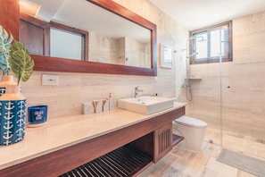A modern bathroom with a large mirror, a sink, and a shower.