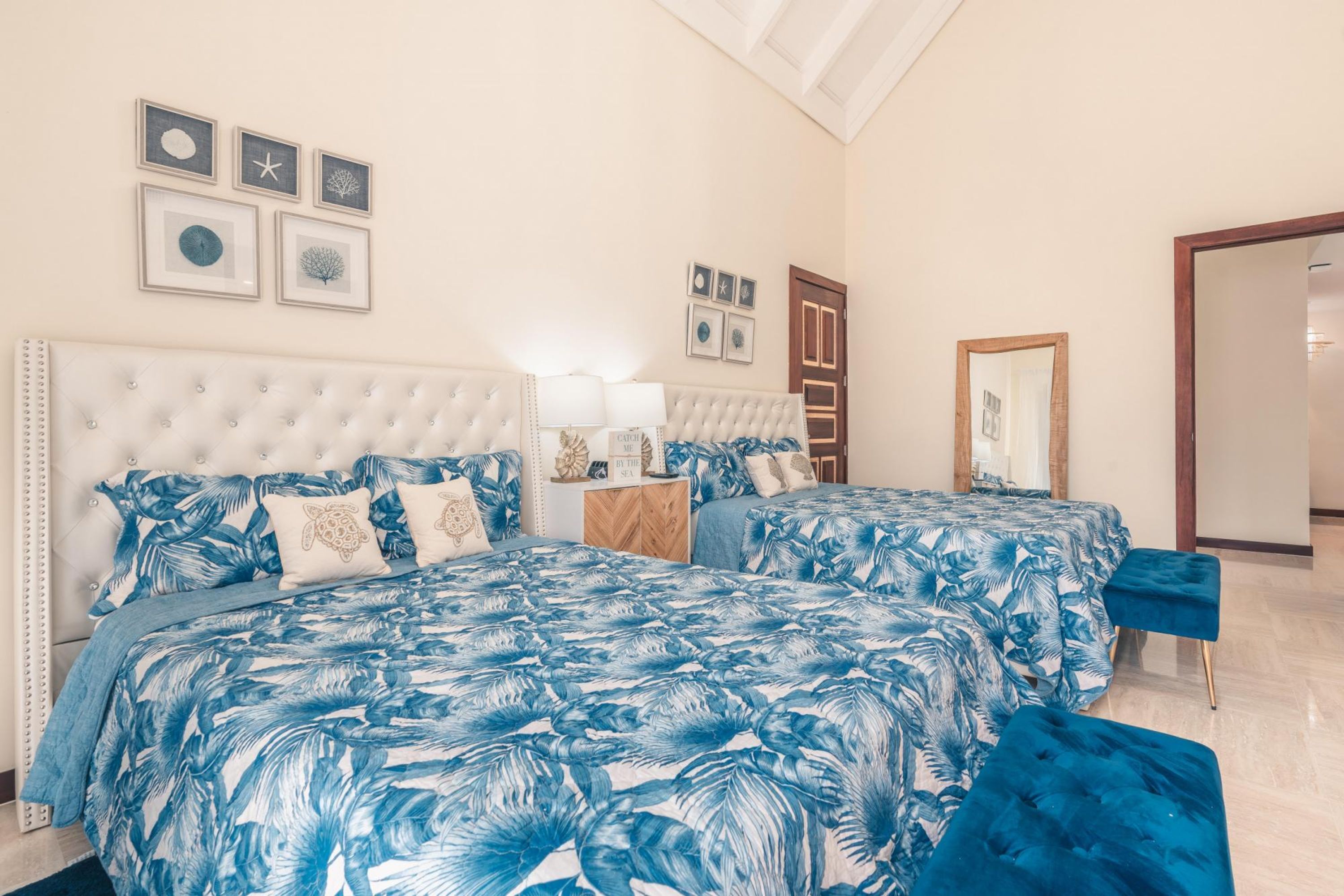 A bedroom with a large bed, two bedside tables, a nightstand, and a mirror.
