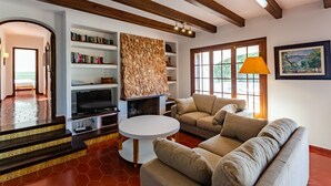 Ein Wohnzimmer mit Kamin, Bücherregalen, einer Couch und einem Fernseher.