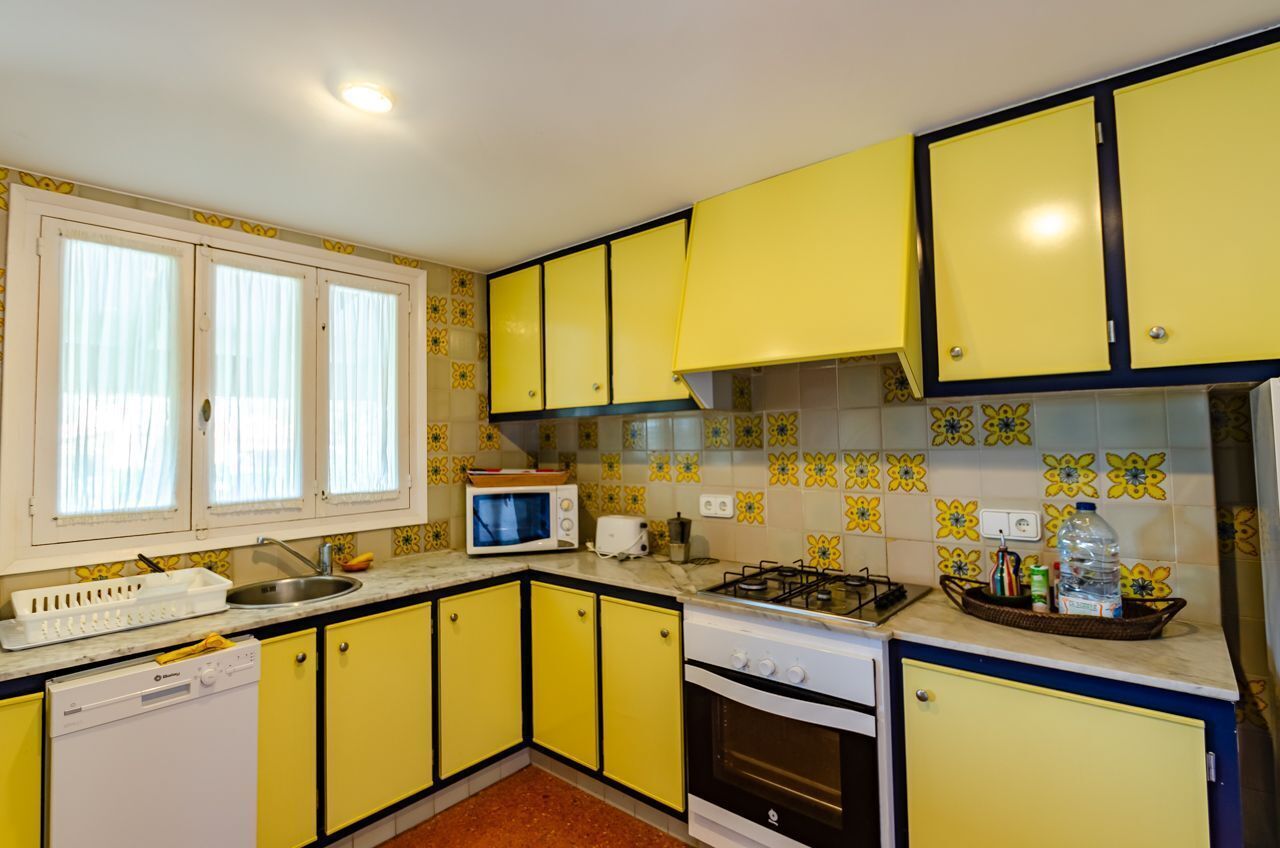 A compact kitchen with yellow cabinets, a microwave, a toaster, and a sink.