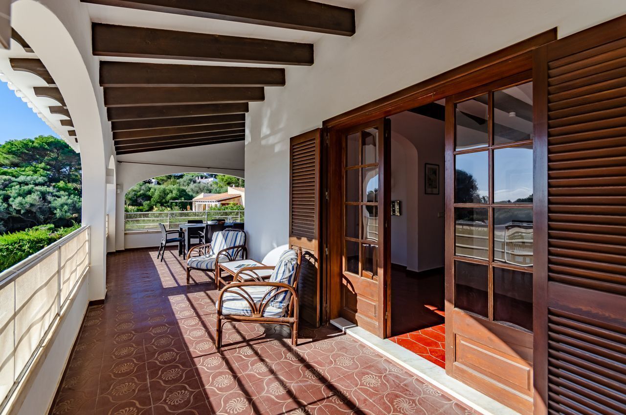 A covered outdoor area with a patio, chairs, and a wooden door.