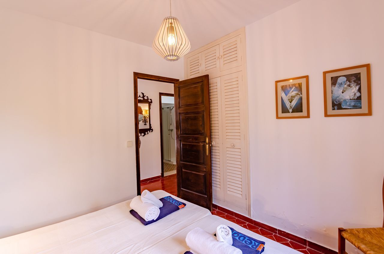 Een hotelkamer met een bed, een houten deur, een spiegel en twee afbeeldingen in lijsten aan de muur.