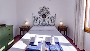 Ein Hotelzimmer mit einem großen Bett, zwei Nachttischen mit Lampen, einer grünen Kommode und einem dekorativen Wandbild.