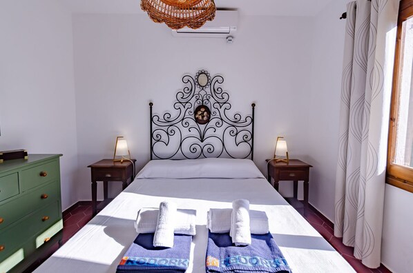 A hotel room with a large bed, two bedside tables with lamps, a green dresser, and a decorative wall hanging.