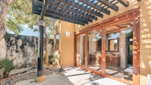 A modern outdoor bathroom with a glass enclosure, a wooden bench, and a stone wall. - Tropical Villa With Pool at Green Village B843 (Punta Cana)