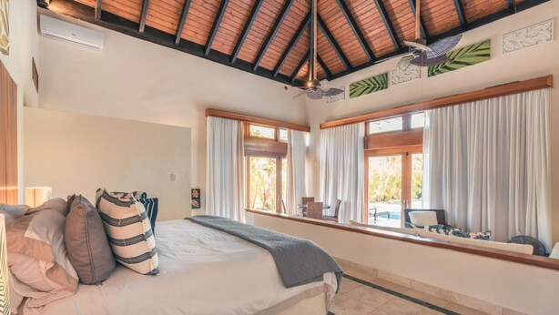 A bedroom with a bed, curtains, a window with a view, and a ceiling fan. - Tropical Villa With Pool at Green Village B843 (Punta Cana)