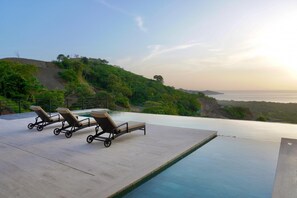 Ein Infinity-Pool mit Liegestühlen und Blick aufs Meer.