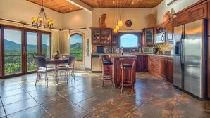 A spacious kitchen with a large island, wooden cabinets, and a stainless steel refrigerator. - Flamingo Rose Vista in Playa Flamingo (Cabo Velas)