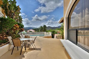 A patio with a pool, outdoor seating, and a view of mountains.