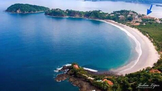 An aerial view of a coastal area with a beach, a small island, and a large body of water.
