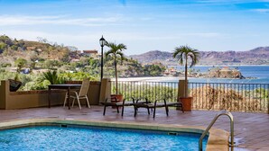 A swimming pool with a view of the ocean and hills.