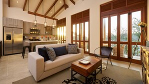 A spacious living area with a sofa, coffee table, and a view of the outdoors through large windows.