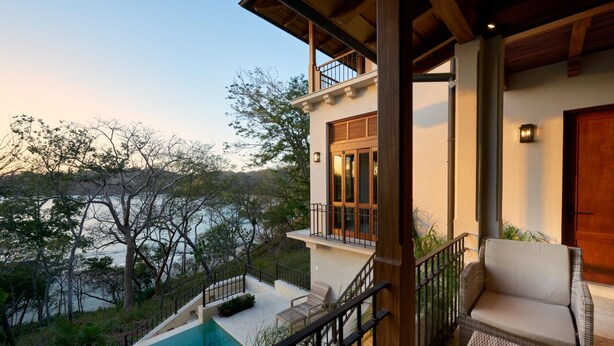 A modern building with a balcony, a pool, and a view of a natural landscape.