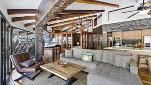 Un vaste espace de vie comprenant un grand canapé, une table basse en bois et un mur en pierre.