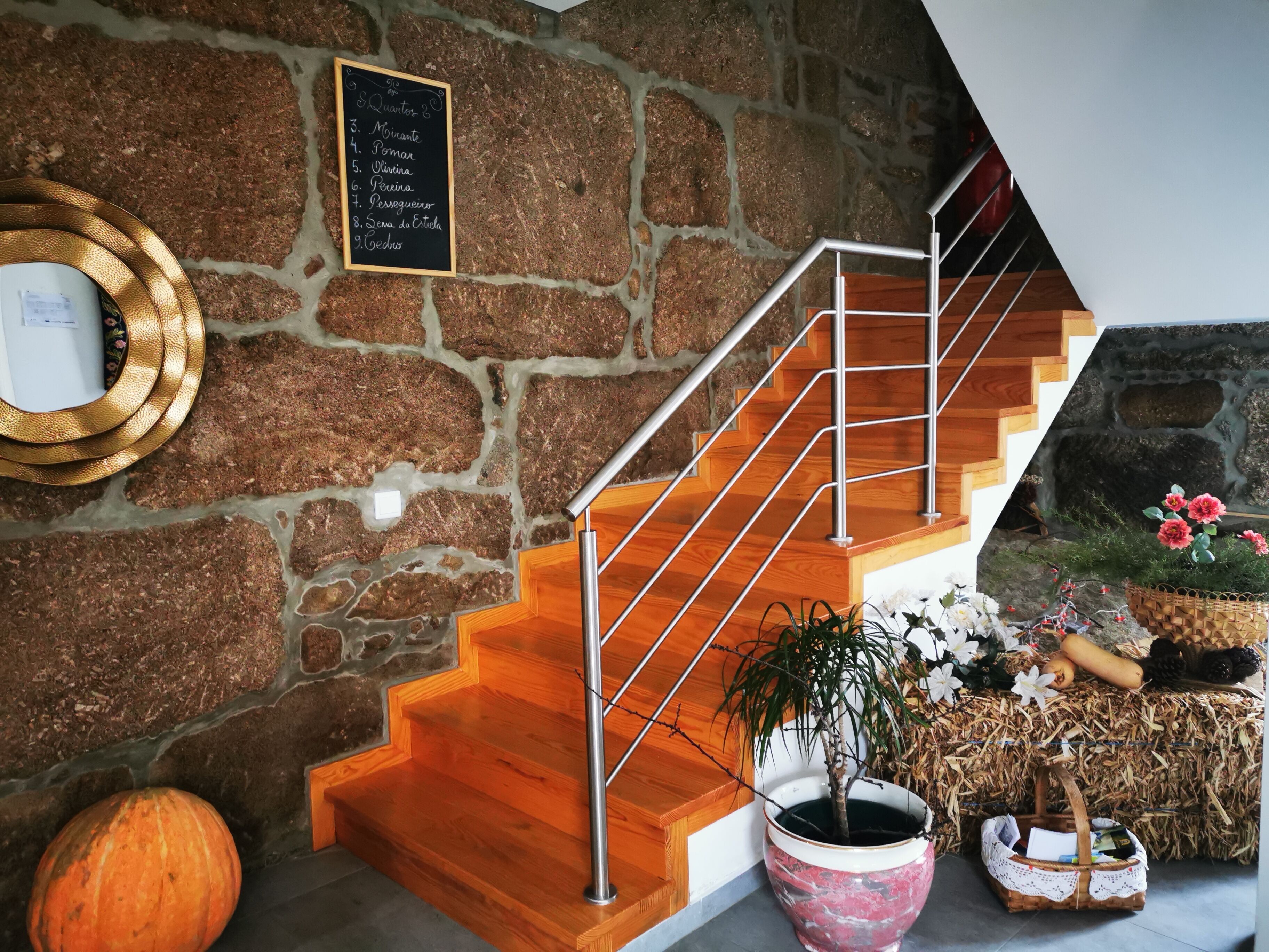 A staircase with a stone wall, a wooden handrail, and a potted plant.