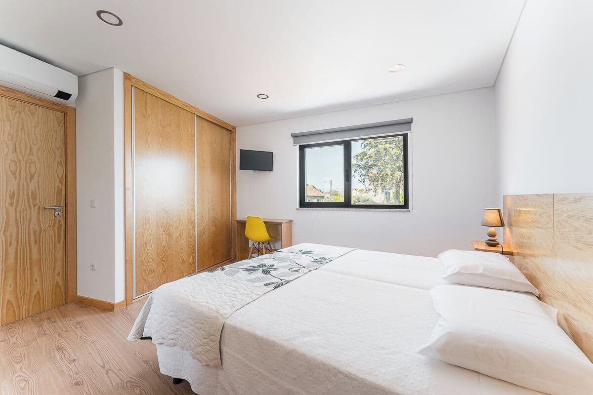 Une chambre à coucher avec un lit, un bureau, une chaise et une fenêtre.