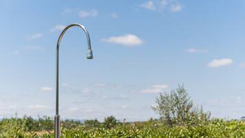 A single metal faucet against a clear sky and dense greenery.