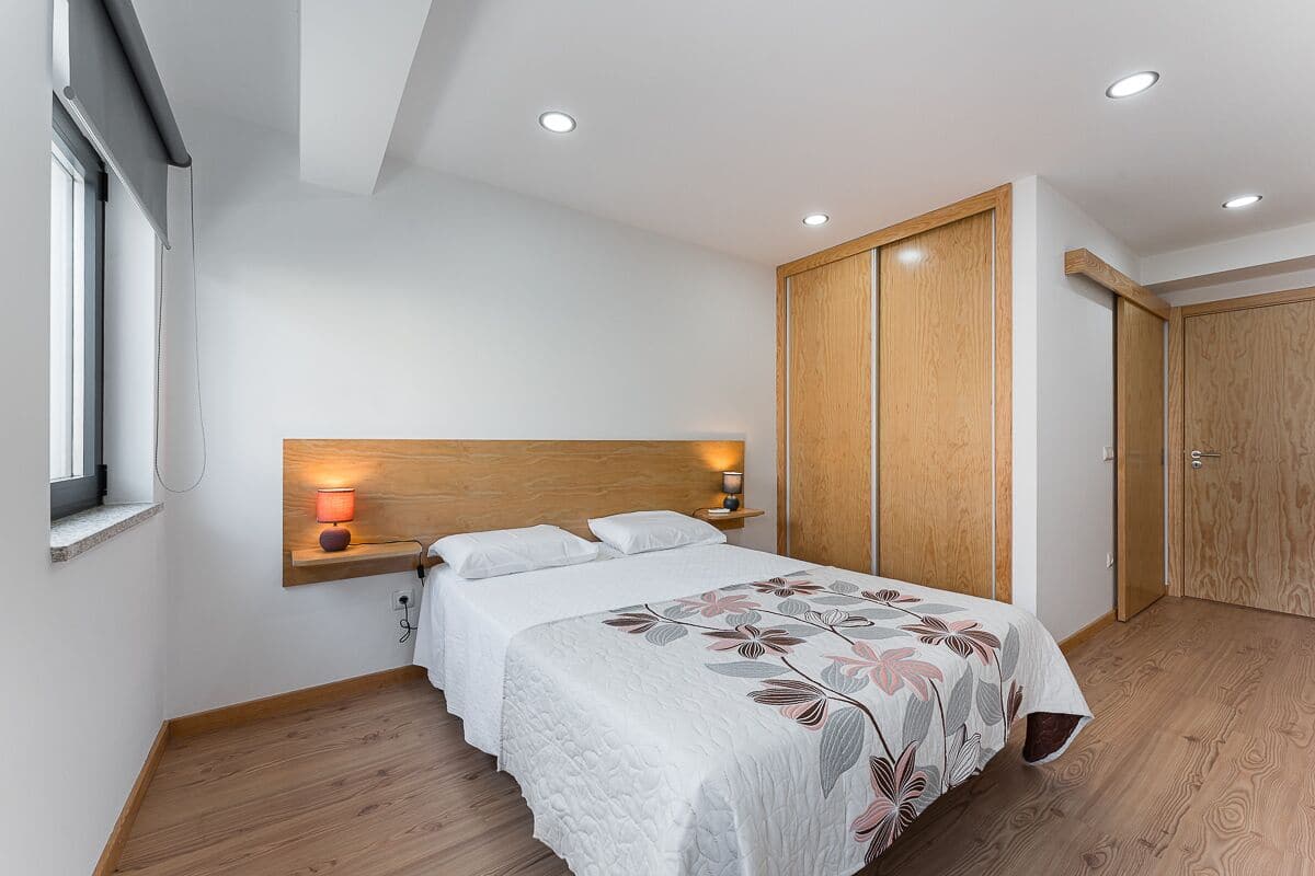 Une chambre à coucher avec un lit, une table de chevet, une lampe, une armoire et une fenêtre.