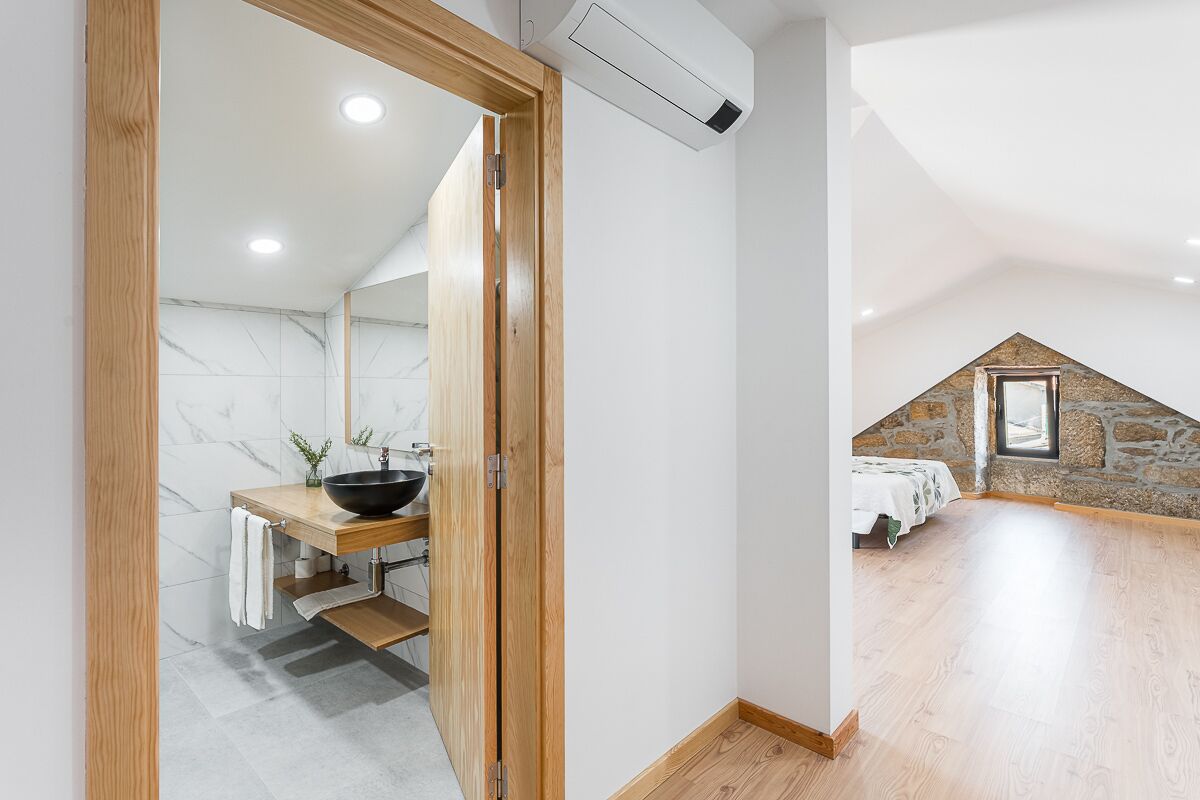 Un baño moderno con tocador de madera, lavabo negro y salpicadero de mármol.