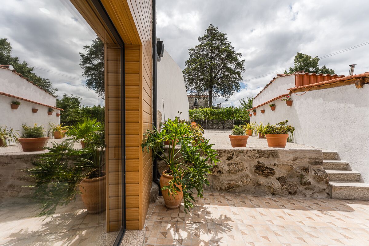 A courtyard with potted plants, a stone wall, and steps leading to a higher level.