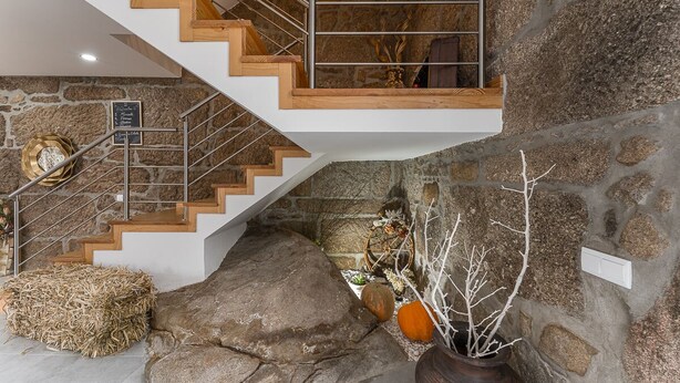 A modern staircase with wooden steps and metal railings, leading to a loft area with a stone wall and rustic decor. - Sevenfarm (Mangualde)