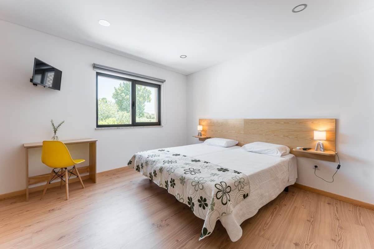 Une chambre à coucher avec un lit, des lampes de chevet, un bureau, une chaise et une fenêtre.